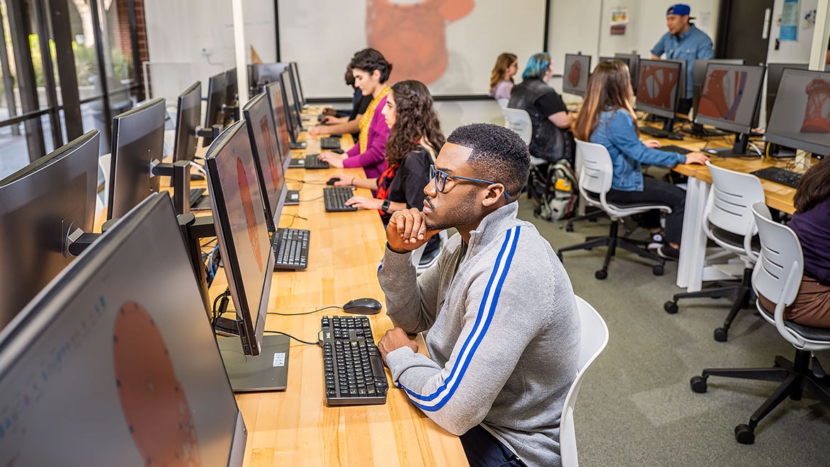 Long desk with row of four people working on their computers