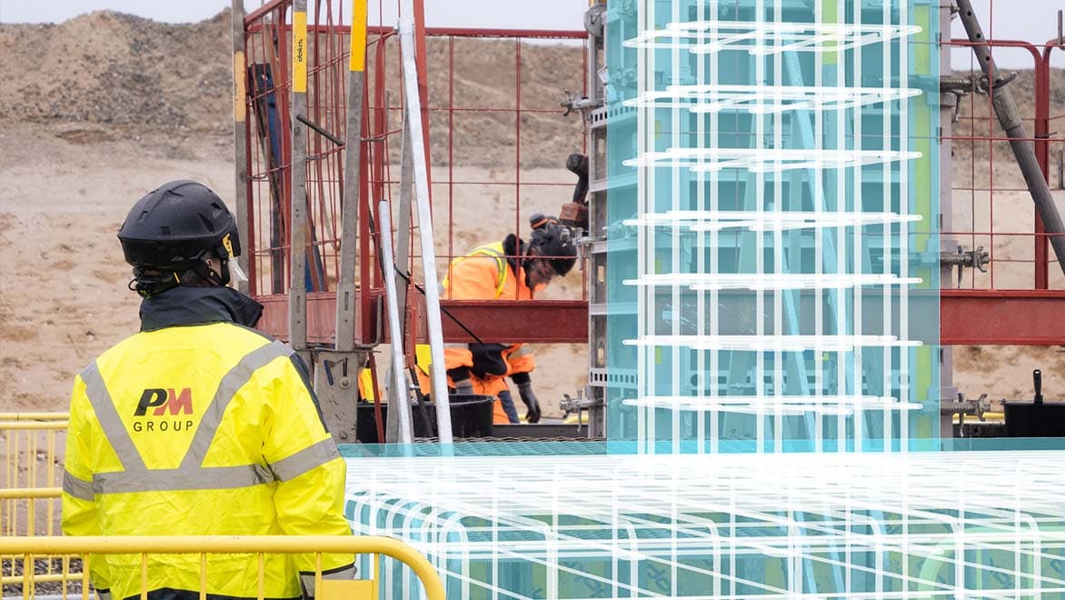 PM Group construction workers on a job site with a digital overlay of the building structure 